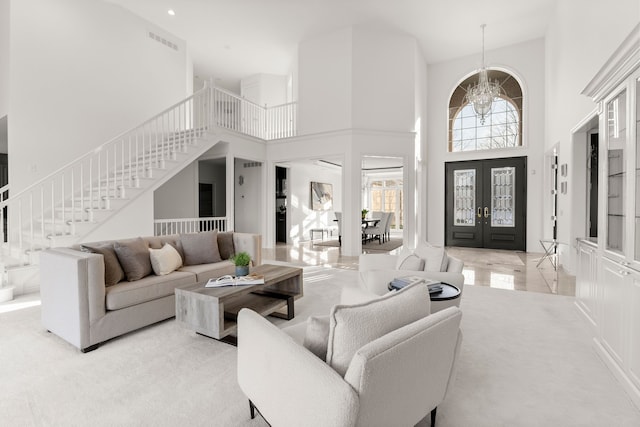 living room with a chandelier, light colored carpet, a high ceiling, and french doors