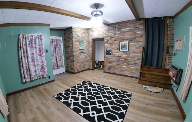 interior space with hardwood / wood-style flooring, brick wall, heating unit, and beam ceiling