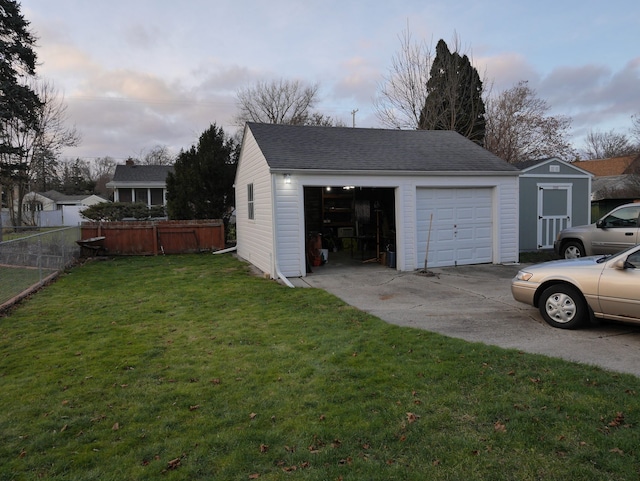 garage at dusk featuring a lawn