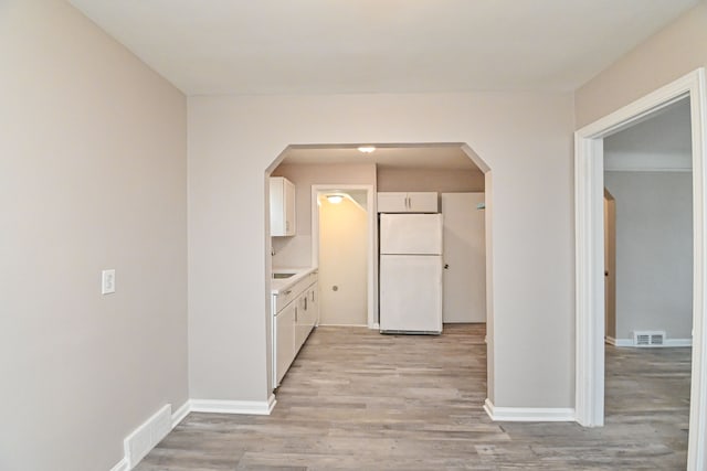 kitchen featuring white cabinets, white fridge, and light hardwood / wood-style floors