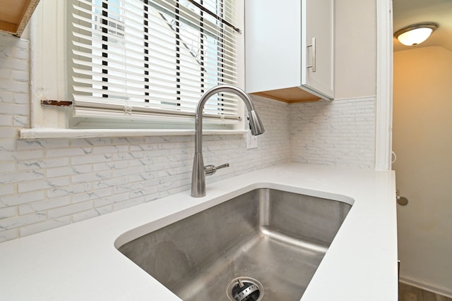 details with backsplash, white cabinetry, and sink