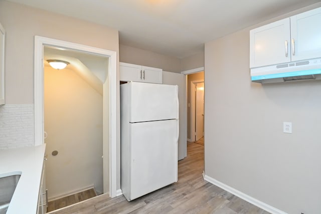 kitchen with white cabinetry, sink, light hardwood / wood-style floors, and white refrigerator