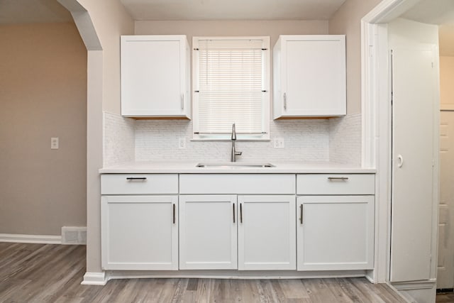 kitchen featuring backsplash, light wood-type flooring, white cabinetry, and sink