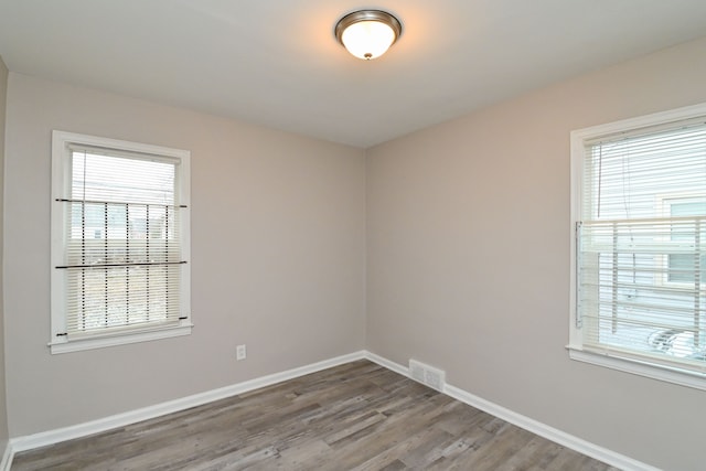 empty room with a healthy amount of sunlight and hardwood / wood-style flooring