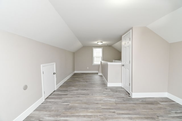 additional living space featuring vaulted ceiling and light wood-type flooring