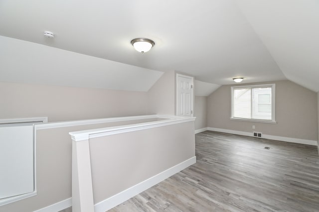 bonus room with hardwood / wood-style floors and vaulted ceiling