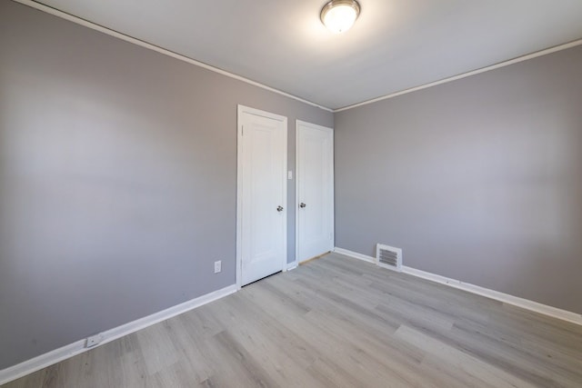 unfurnished bedroom with light wood-type flooring, ornamental molding, and a closet