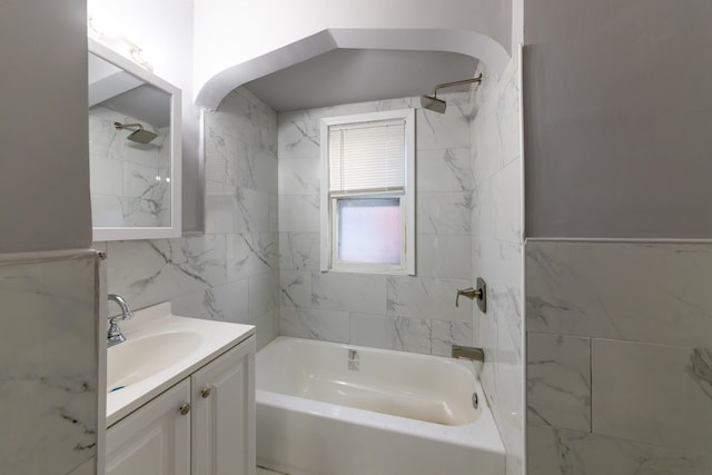 bathroom with tiled shower / bath combo, tile walls, and vanity