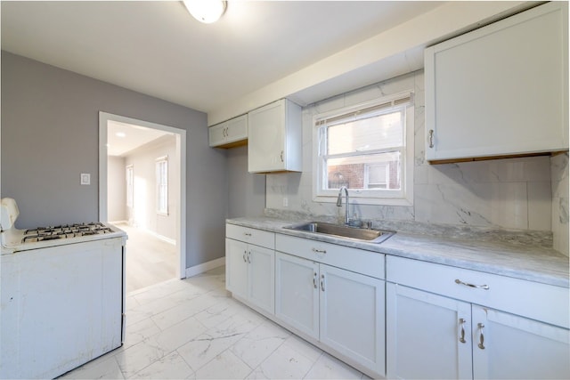 kitchen featuring tasteful backsplash, white cabinetry, sink, and white gas range oven