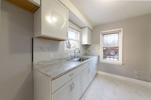 kitchen featuring white cabinets, decorative backsplash, and sink