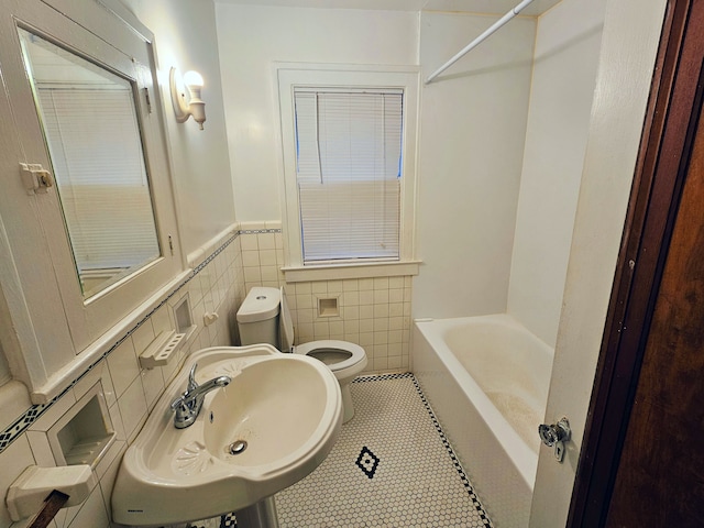 full bathroom with sink, tile patterned flooring, toilet, tile walls, and tub / shower combination