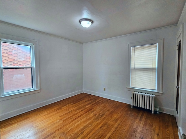 spare room with hardwood / wood-style floors, radiator, and crown molding