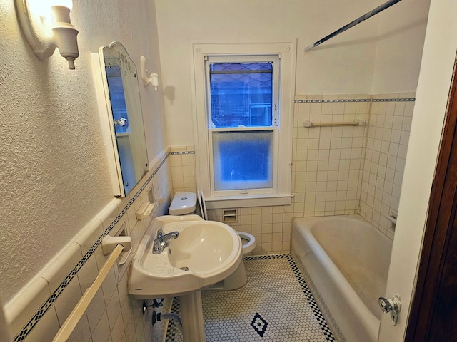 bathroom featuring toilet, tile patterned floors, tile walls, and sink