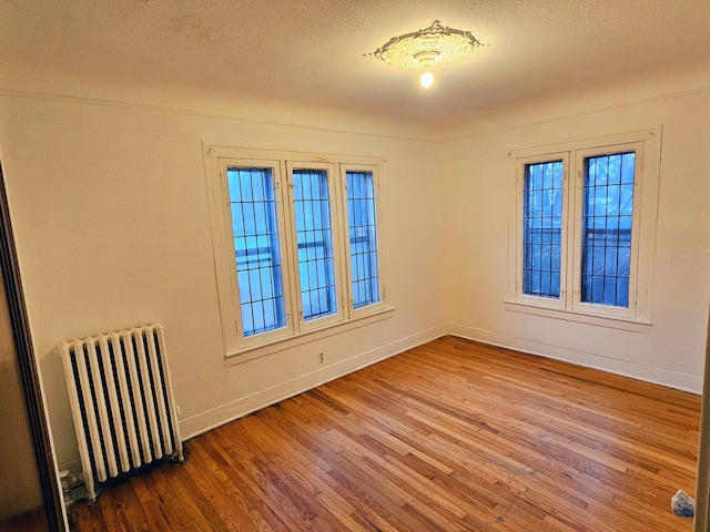 unfurnished room featuring hardwood / wood-style floors, a textured ceiling, and radiator