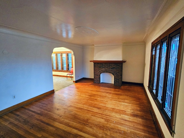 unfurnished living room featuring hardwood / wood-style flooring and a brick fireplace