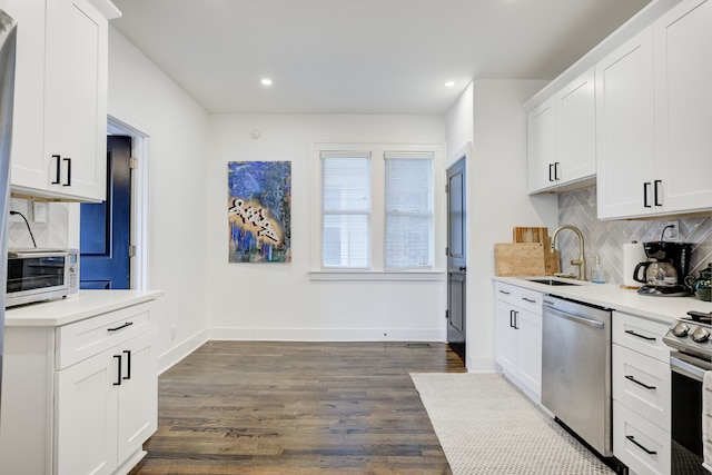 kitchen with sink, dark wood-type flooring, stainless steel appliances, decorative backsplash, and white cabinets