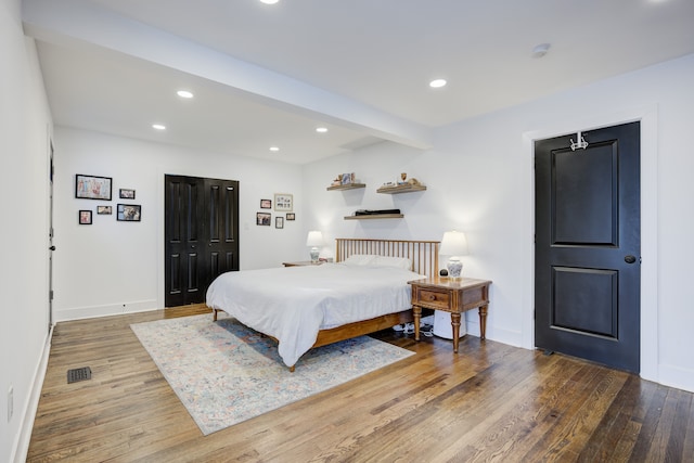 bedroom with beam ceiling, a closet, and hardwood / wood-style floors