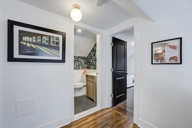 corridor with vaulted ceiling and dark wood-type flooring