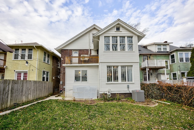 rear view of property with central AC unit, a balcony, and a lawn