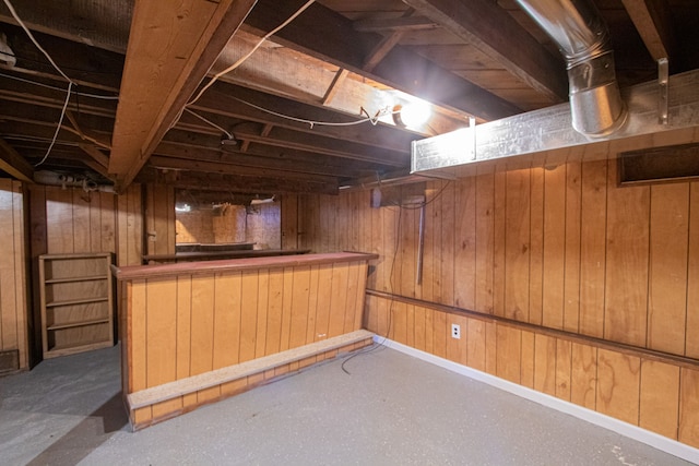 basement featuring bar and wooden walls