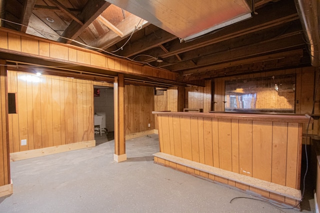 basement featuring bar area, electric panel, and wooden walls