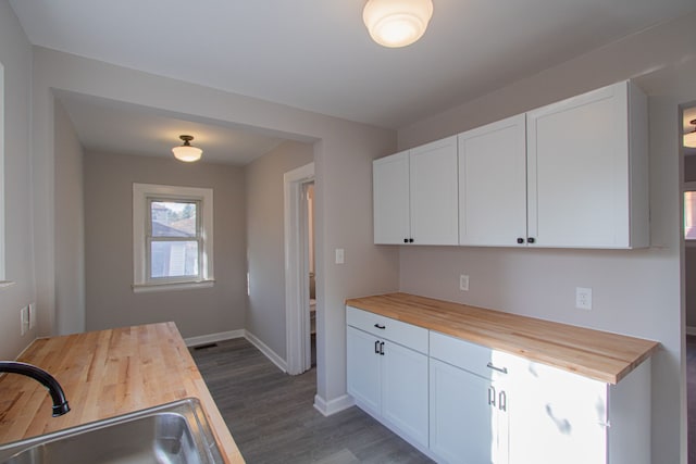 kitchen featuring butcher block counters, sink, white cabinets, and dark hardwood / wood-style floors