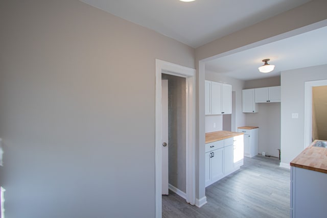 kitchen featuring white cabinets, light wood-type flooring, and butcher block counters