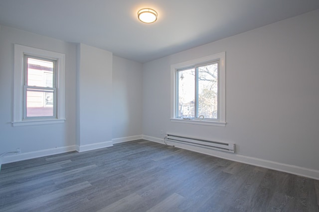 empty room with dark hardwood / wood-style flooring and a baseboard heating unit