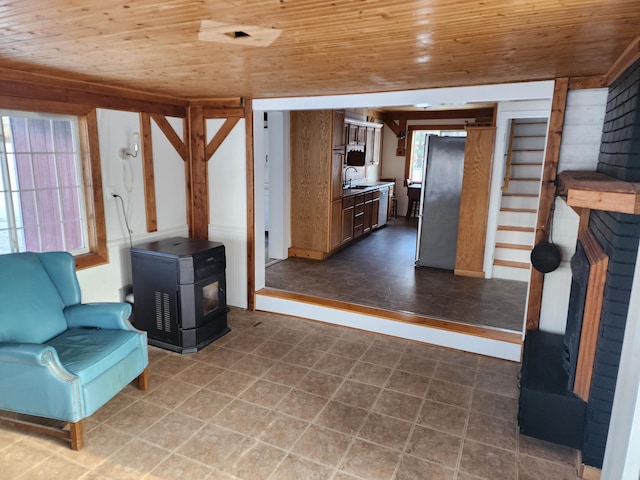 unfurnished room with a wood stove, a wealth of natural light, and wooden ceiling