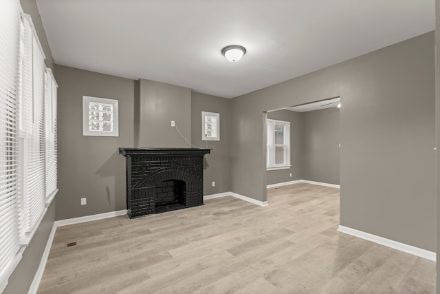 unfurnished living room featuring light hardwood / wood-style floors, a fireplace, and a wealth of natural light