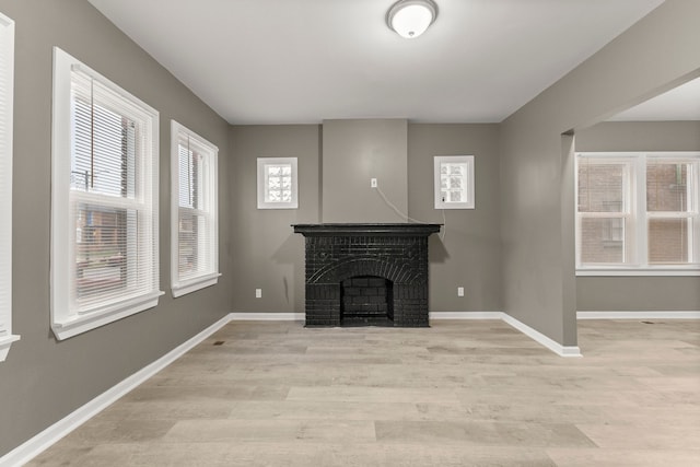 unfurnished living room with a fireplace, light wood-type flooring, and a wealth of natural light