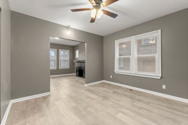 unfurnished living room featuring ceiling fan, a fireplace, and light hardwood / wood-style floors