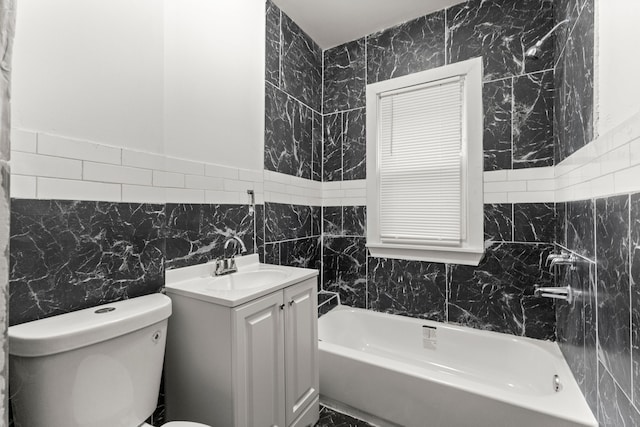 bathroom featuring vanity, toilet, tile walls, and a tub