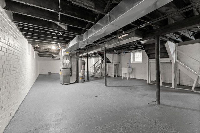 basement featuring heating unit, sink, and gas water heater