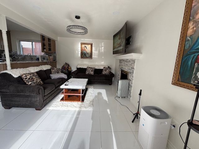 living room featuring a stone fireplace, sink, and light tile patterned floors