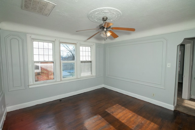 unfurnished room with ceiling fan, dark wood-type flooring, and a textured ceiling