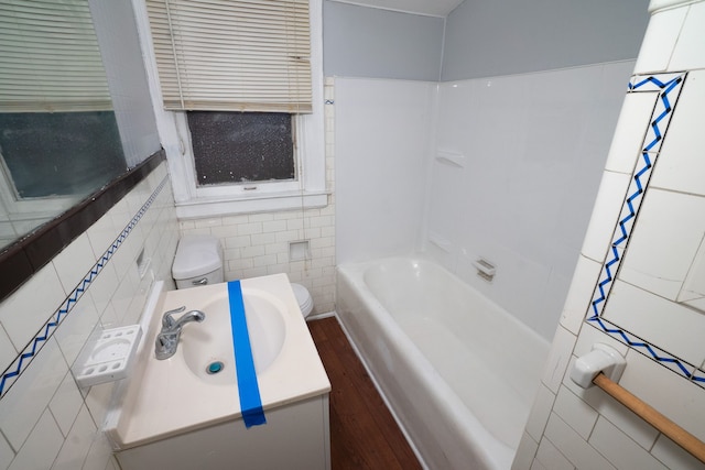 bathroom with vanity, hardwood / wood-style flooring, toilet, and tile walls