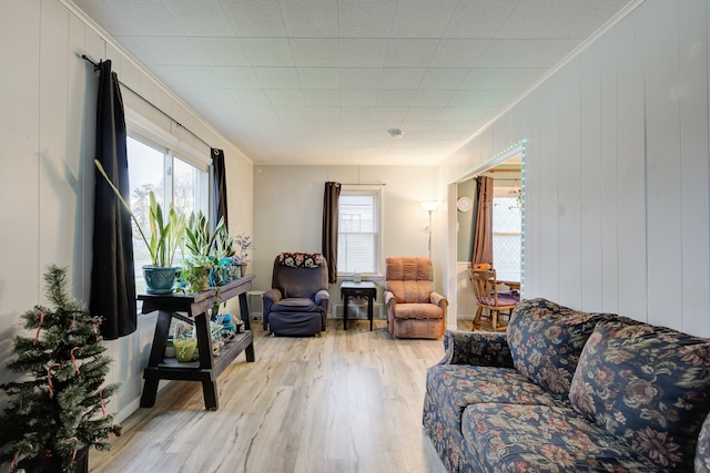 living room with crown molding, light hardwood / wood-style flooring, and wooden walls