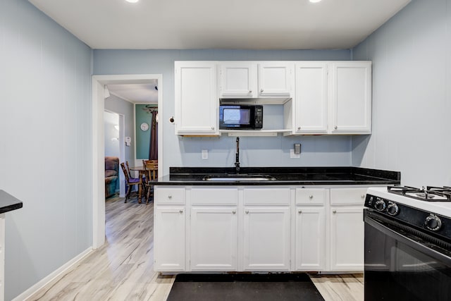 kitchen featuring sink, white cabinets, black appliances, and light wood-type flooring