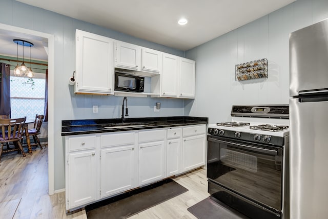 kitchen featuring black appliances, white cabinetry, light wood-type flooring, and sink