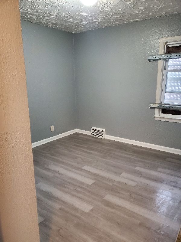 spare room featuring hardwood / wood-style floors and a textured ceiling