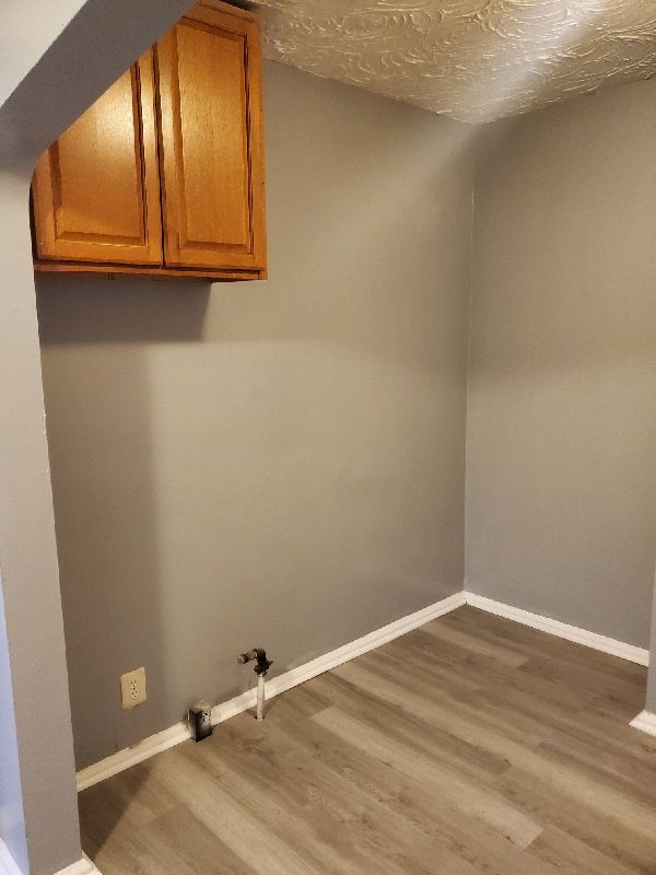 clothes washing area featuring hardwood / wood-style floors, cabinets, and a textured ceiling