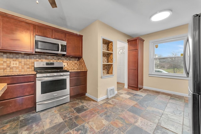 kitchen with backsplash, light stone countertops, and appliances with stainless steel finishes