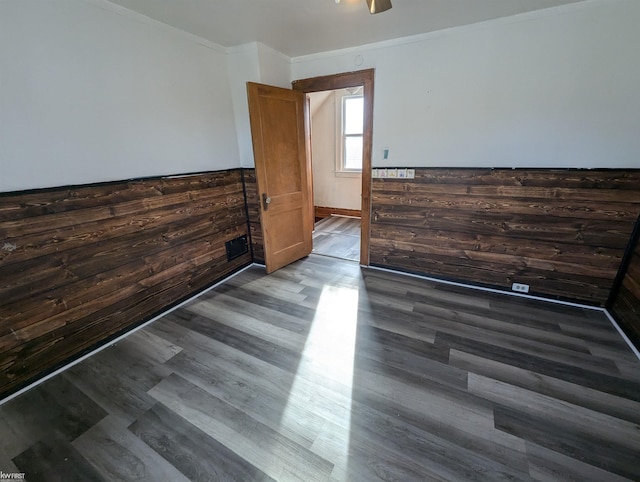 empty room with hardwood / wood-style floors, ornamental molding, and wooden walls