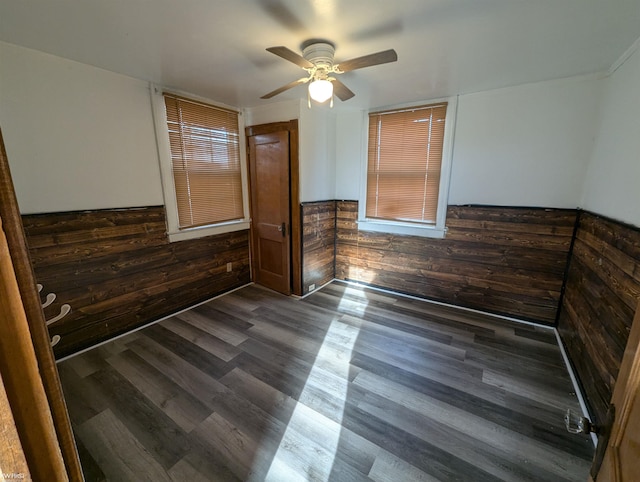 interior space featuring ceiling fan, dark hardwood / wood-style floors, and wooden walls