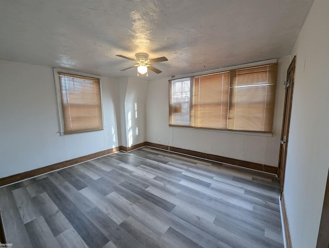 empty room with ceiling fan, wood-type flooring, and a textured ceiling