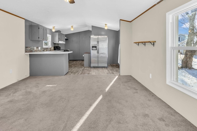 kitchen featuring kitchen peninsula, stainless steel fridge, carpet, gray cabinetry, and lofted ceiling