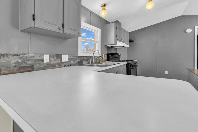 kitchen featuring gray cabinetry, black gas range, sink, vaulted ceiling, and a textured ceiling