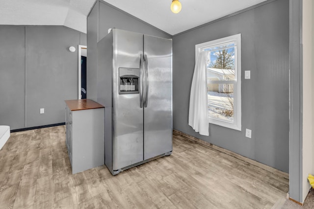 kitchen featuring stainless steel fridge with ice dispenser, light hardwood / wood-style flooring, lofted ceiling, and wood counters