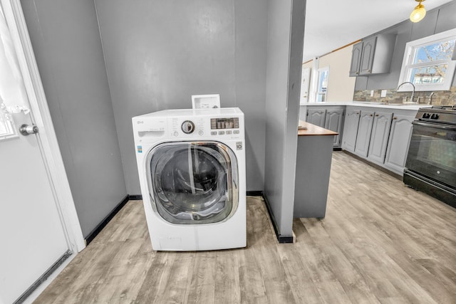 laundry room with washer / dryer, sink, and light hardwood / wood-style flooring